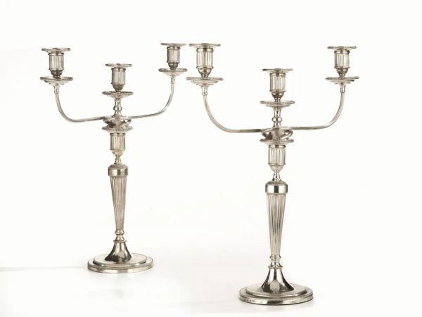  Due candelabri, Londra, 1789 e Londra 1887  in argento, fusto a colonna rastremata e scanalata su base circolare, ciascuno a due bracci ricurvi per complessive tre luci. I candelabri sono trasformabili in candelieri, alt. cm 45,5, basi appesantite (2)                                              