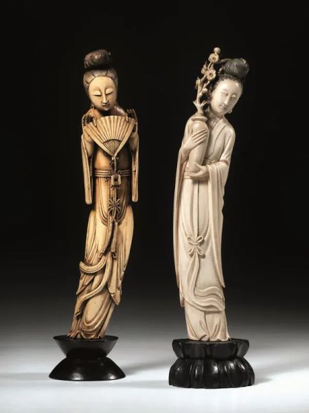  Due Guanyin, Cina inizI sec. XX,  in avorio intagliato, una reggente un ventaglio e l'altra un vaso con ramo di pesco, alt. cm 30; alt. cm 29,5 (2)