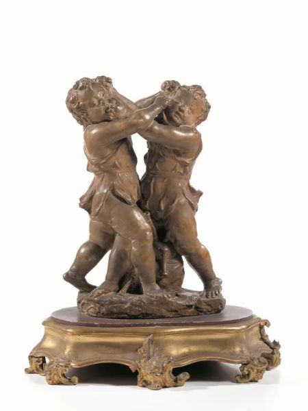 Scultura, manifattura di Signa, fine sec. XIX, in terracotta, raffigurante due putti in lotta per una zampogna situata fra di loro, alt. cm 44, poggiante su base in legno intagliato e dorato cm 11x27x48, piccoli danni&nbsp;