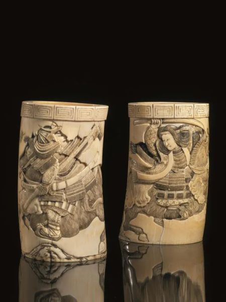 Due vasi porta pennelli, Giappone sec. XIX, in avorio, decorati con figure di samurai a cavallo, profilo superiore a nuvole stilizzate, alt cm 15, fondi mancanti (2)