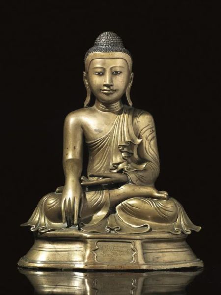  Buddha, area birmana, sec. XIX,  vestito con vesti svolazzanti e seduto su una base a plinto in dhyanasana, la mano sinistra in dhyana mudra, e la destra bhumisparsa  mudra, sul fronte della base un iscrizione, alt. cm 45 