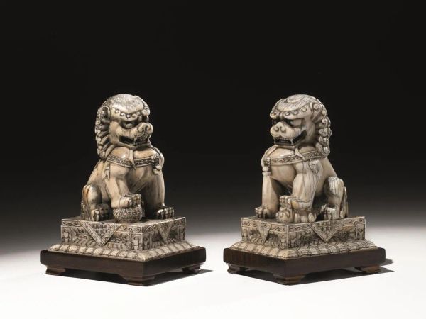 Coppia di cani di Pho, Cina sec. XVIII-XIX, in avorio, finemente scolpiti e poggianti su base squadrata in legno, alt. cm 13.2
