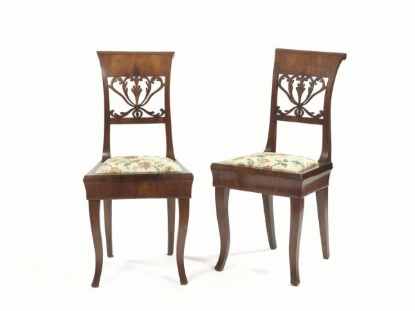  Coppia di sedie, 1830 circa,  in noce a patina chiara, spalliera rettangolare,   cartella traforata a volute vegetali, gambe mosse, sedili ricoperti in seta operata (2)         