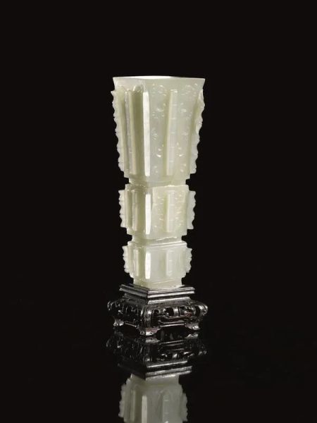 Vasetto, Cina sec. XVIII-XIX, di forma arcaica &quot;Gu&quot;, in giada celadon finemente intagliata, decorato a teste di fenici affrontate, alt. cm 12,4, su base in legno