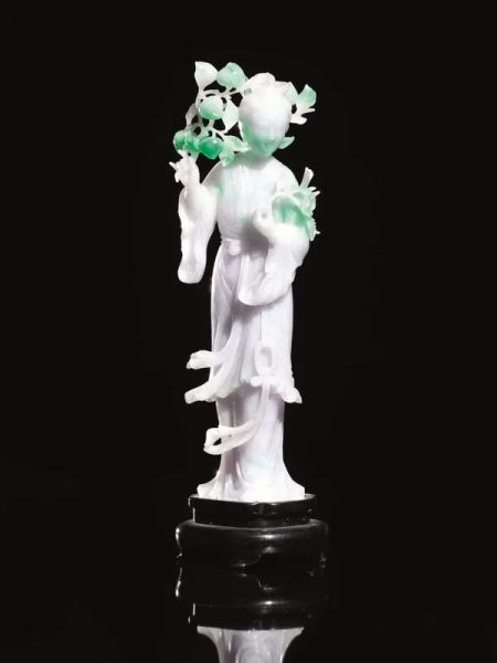  Intaglio, Cina sec. XIX-XX , in giadeite nei toni del verde pallido e smeraldo, raffigurante Guanyn stante con rami di pesco tra le mani, alt. cm 22, su base in legno alt. cm 4 