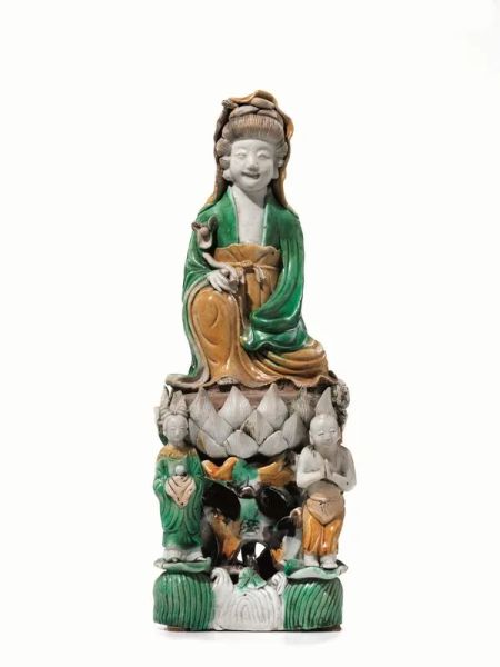 Scultura Cina sec. XIX, in porcellana smaltata &quot;sancai&quot;, raffigurante Guanyin assisa su fior di loto sorretto da due attendenti, alt. cm 32