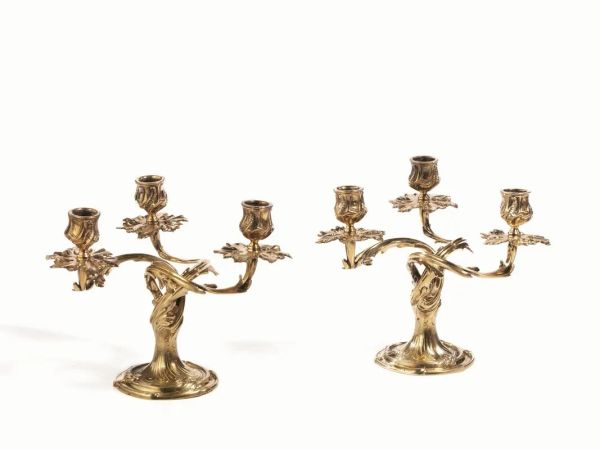  Coppia di candelabri, Copenaghen, metÃ  sec. XX,  in argento dorato, a tre bracci ciscuno a volute di foglie, basi circolari, alt. cm 19, g 2620 (2)  