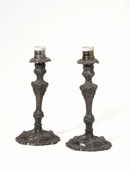  Coppia di candelieri,  in argento sbalzato e cesellato a volute, fusto a balaustro su base circolare sagomata, alt. cm 26, adattati ad elettricitÃ  (2)                                                  