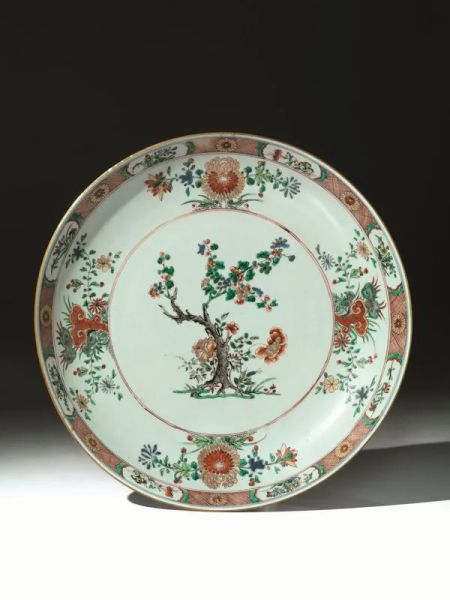 Piatto,  Cina sec. XVIII, epoca Yongzheng (1723-1735),  in porcellana della famiglia Verde   yingcai,  il centro decorato con albero di pruno fiorito contornato da peonie e bambÃ¹  sulla tesa crisantemi, loto e funghi linghzi, diam. cm 31