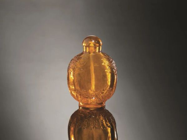  Snuff-bottle, Cina dinastia Qing (1644-1911),  in ambra, le anse finemente intagliate a teste di draghi, la base con onde stilizzate, alt. cm 6,5 (2)