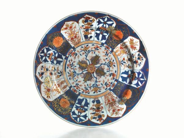  Grande piatto, Cina, periodo Kangxi (1661-1722),  in porcellana Imari, decorato al centro da melograni e sulla tesa da sedici riserve a motivi floreali, marchio della losanga, diam cm 39