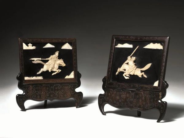 Coppia di piccoli paravento da tavolo, Cina fine dinastia Qing (1644-1911), decorati con figure a rilievo di guerrieri, montati su supporti in legno intarsiato, cm 15x15,5