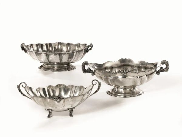  Tre vaschette,  di forma ovale, in argento, piccoli manici modellati a volute vegetali, poggianti su basso piedestallo, una su piedini a riccioli vegetali, g 1425 (3)