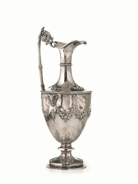 Versatolo, Londra, 1868, in argento di forma tronco conica con decoro a teste di caprone in rilievo che trattengono un festone di fiori, base circolare, ansa unita al corpo da doppia voluta, alt. cm 34,5, g 840