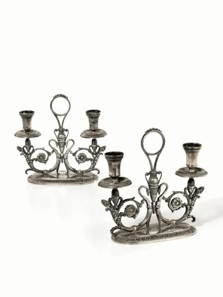  Coppia di candelabri,  in argento, corpo configurato a volute vegetali e cigni, base ovale con motivi a piccole foglie lanceolate, alt. cm 20, gr. 1600