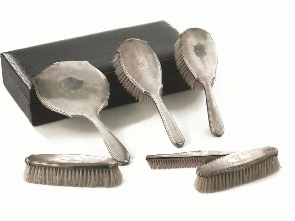Servito da toilette, Birmingham, 1924, composto di uno specchio a mano, quattro spazzole ed un pettine in argento lavorato guilloch&eacute; con iscrizione Tressie, entro scatola (6)