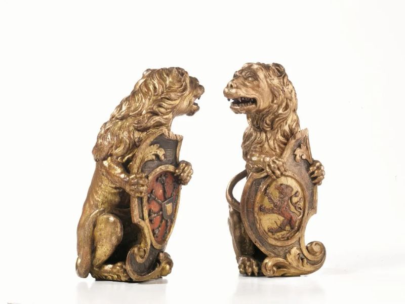 Coppia di sculture, Venezia, sec. XVII, in legno dorato e parzialmente laccato in rosso raffiguranti leoni reggiscudo. Il primo sostiene con le zampe anteriori uno  - Asta Importanti Mobili, Arredi e Oggetti d'Arte - Pandolfini Casa d'Aste