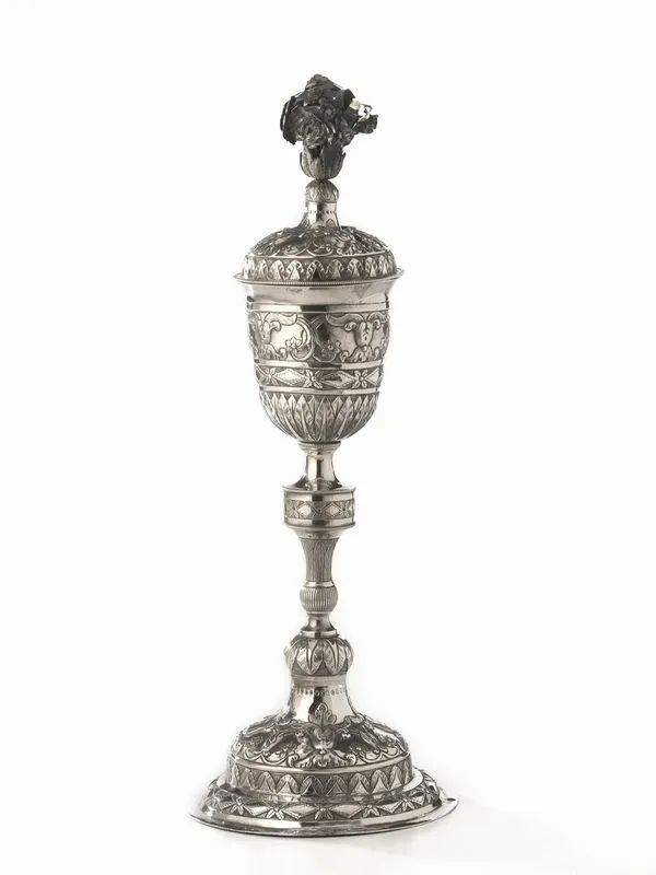 Calice con coperchio, Torino, 1820 circa, in argento, base circolare bombata e sbalzata con nastro di fiori e rombi e girali floreali, fusto a balaustro con nodo circolare decorato da nastro, sottocoppa cesellato a foglie lanceolate ed elementi decorativi analoghi a quelli del fusto e della base; coperchio con finale realizzato da mazzetto di fiori, alt. cm 43, g 730  - Asta Argenti e Numismatica - II - Pandolfini Casa d'Aste