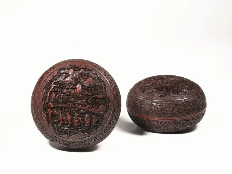  Coppia di scatole Cina sec. XVIII-XIX,  in lacca, a doppia faccia, di forma circolare leggermente bombata, ciascuna finemente intagliata con motivi analoghi, la parte superiore decorata con figure in un giardino, con palazzo retrostante, la parte inferiore decorata con cavallette e farfalle in mezzo a dei motivi floreali, diam cm 17,3,  lievi danni ad una delle due scatole   - Auction Oriental Art - Pandolfini Casa d'Aste