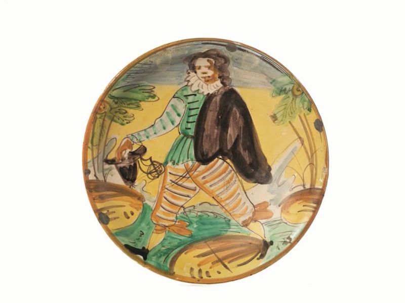 Piatto, Manifattura di Montelupo, fine sec. XIX, in maiolica policroma raffigurante un soldato con cappello in mano in un paesaggio stilizzato, cm 32, lievi cadute di smalto  - Auction European Furniture - Pandolfini Casa d'Aste